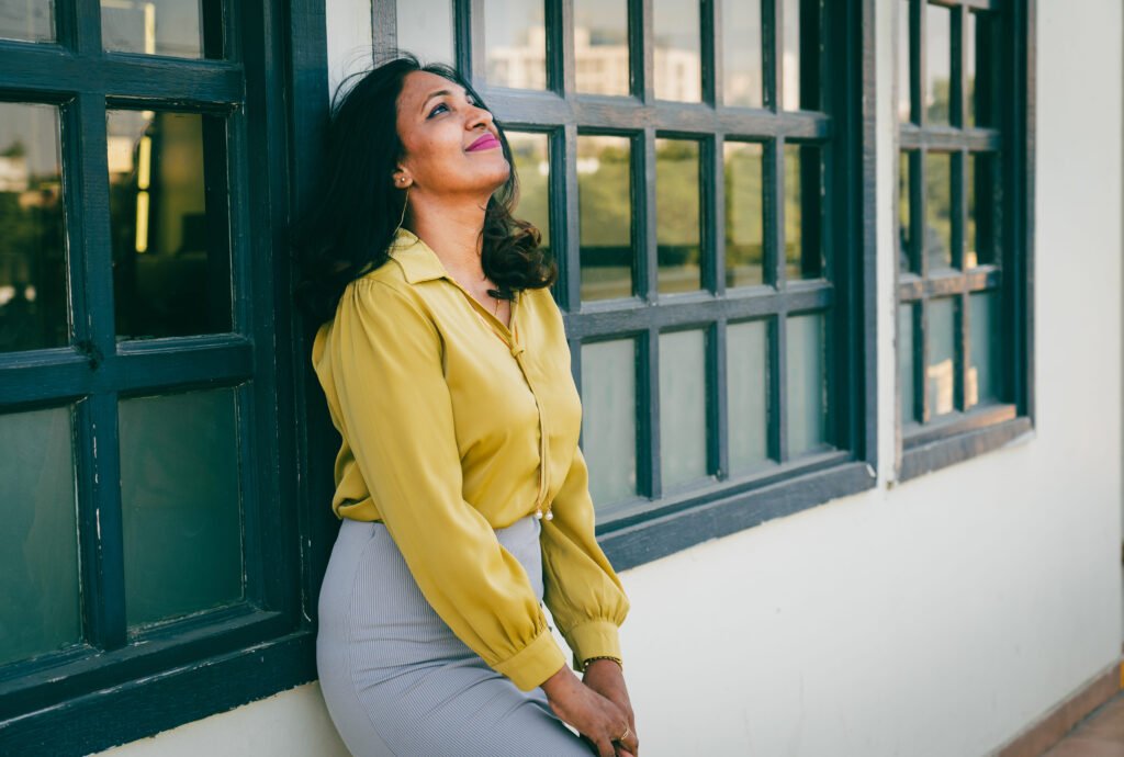 businesswoman leaning against wall windows head tipped back